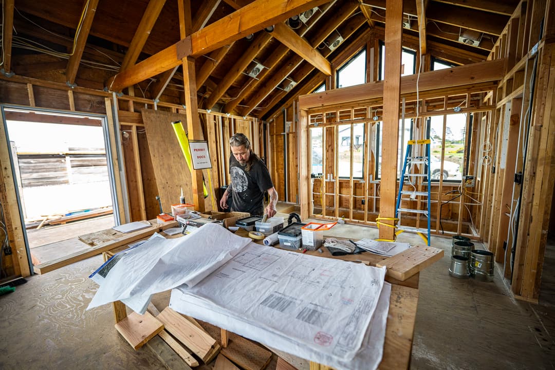 a man reading building plans in a newly framed building